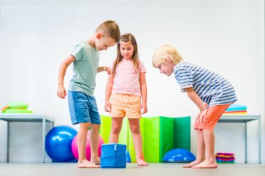 Young children playing during group therapy session. Child occupational physical therapy. Bilateral coordination.