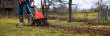 Bahçıvan, ekin ekmek için bahçe yatakları topluyor. Rotovator, bahçe dümeni ya da döner dümen. Ekiciler sıkıştırılmış toprağı parçalar, yapısını ve havasını geliştirir. Bahar bahçıvanlığı.