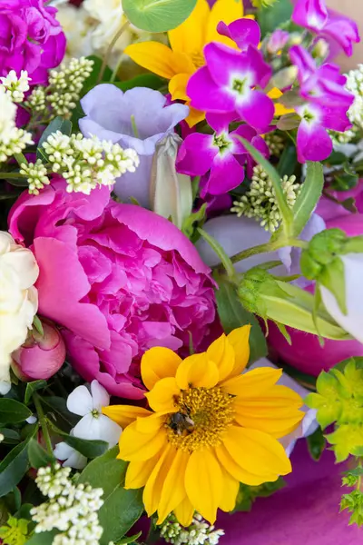 Karışık bahar çiçeklerinden yapılmış çiçek buketi. Güzel canlı renkli taze çiçekler düzenlemesi. Şakayık ve ayçiçekli doğum günü buketi.