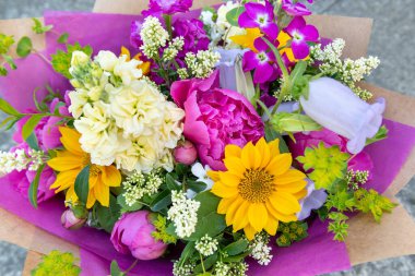 Karışık bahar çiçeklerinden yapılmış çiçek buketi. Güzel canlı renkli taze çiçekler düzenlemesi. Şakayık ve ayçiçekli doğum günü buketi.