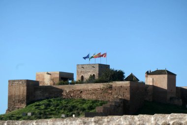 Endülüs köyündeki tarihi Arap şatosunun arkasında Endülüs, İspanya, Alora ve AB bayrakları dalgalanıyor