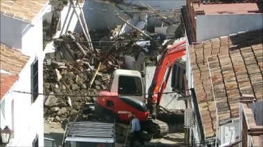 Alora, İspanya - 17 Temmuz 2019: Kazıcı Endülüs köyündeki yıkılmış evdeki yıkıntıları temizliyor. Kazıcı yıkılmış evdeki molozları kaldırıyor
