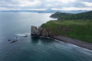 Pasifik Okyanusu 'ndaki yeşil çimlerle kaplı Avacha Körfezi kıyısındaki Kamçatka Yarımadasındaki Deniz Feneri Burnu' nun insansız hava aracı fotoğrafı.