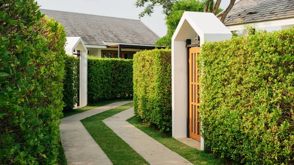 gate house garden in a resort-style setting, with a concrete and grassy walkway.