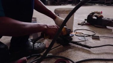 Metali öğütücüyle öğüten endüstriyel işçiler, atölyede uçuşan parlak kıvılcımlar. Metal işçiliği sırasında ellerin ve aletlerin yakın çekimi. Ağır sanayi, güvenlik ve zanaat kavramı