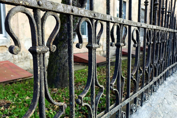 Classic style wrought iron fence from the street around the house with wood and window