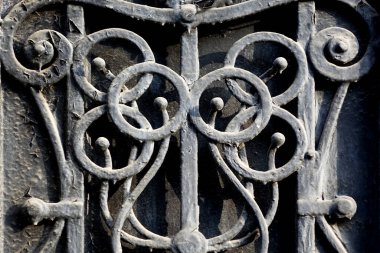 Eski bir bodrum penceresinin tepesinde yüzükler olan, siyah-beyaz boyanmış demir kafes.