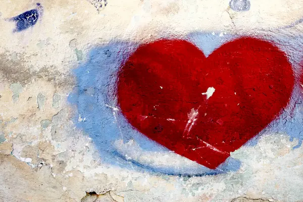 Canlı kırmızı bir kalp, yumuşak mavi renklerle çevrili, dokulu eski bir duvara belirgin bir şekilde resmedilir. Yıpranmış yüzey karakter katar, aşınma aşınması gösterir ve kalbin cesaretiyle güzel bir tezat oluşturur. Bu sanat eserleri bazı duyguları çağrıştırıyor. 