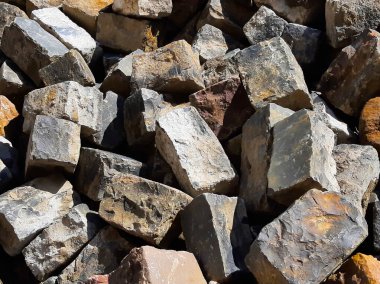 Gündüz vakti bir araya toplanmış çeşitli doku ve renklerde düzensiz tuğlalar..