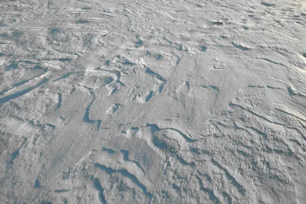 stock image Textured snow surface showcases intricate patterns under the winter sunlight.