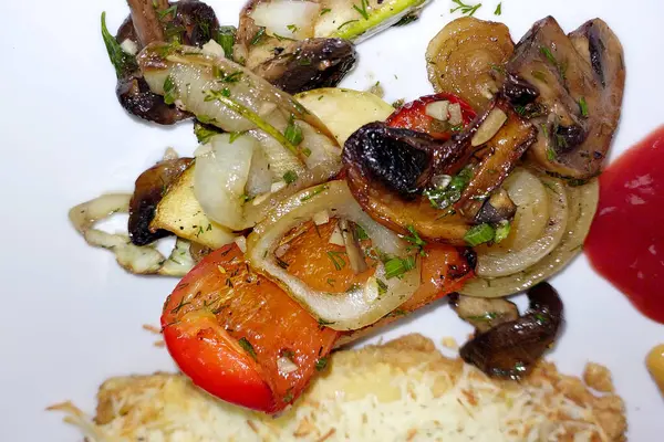 stock image A colorful mix of grilled vegetables, including mushrooms, onions, and bell peppers, garnished and arranged neatly on a white plate.