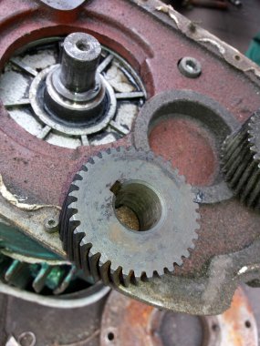 Various gears are positioned on the housing as a technician conducts repairs on mechanical equipment.