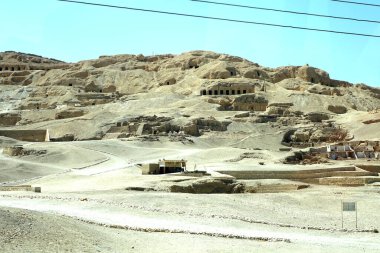 A glimpse of the ancient ruins in Deir el Bahri, showcasing the Valley of the Queens and Valley of the Dead as seen from a bus, reflecting Egypt's rich history and archaeological significance. clipart