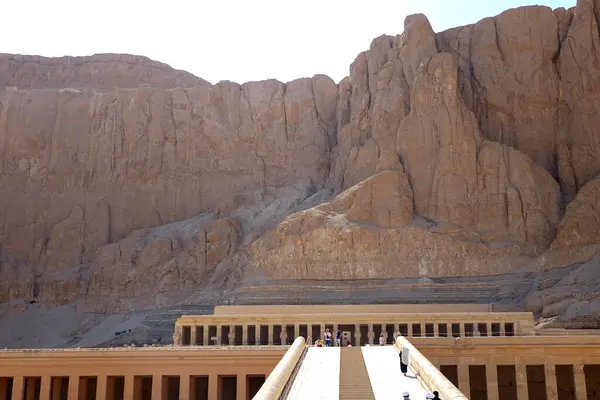 stock image Visitors admire the magnificent ruins of the Mortuary Temple of Hatshepsut, a testament to ancient Egyptian architecture in Deir el Bahri, surrounded by towering cliffs and historical significance.