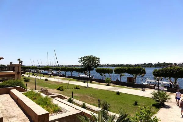 stock image Visitors stroll along the picturesque promenade by the Nile River in Luxor, enjoying the stunning views and vibrant atmosphere of this historic location.