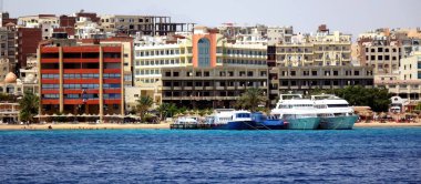 Hurghada, Egypt - July 10, 2017 Urban Hotels Along the Coastline of Hurghada With Boats Docked in the Foreground on a Sunny Day clipart