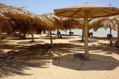 Hurghada 'daki Cennet Adası' ndaki plaj şemsiyelerinden güneş ışığı filtreleri, kumlu bir sahilde rahatlamaya davetiye çıkarıyor. Ziyaretçiler Kızıl Deniz 'in sıcak atmosferinin tadını çıkarıyorlar..