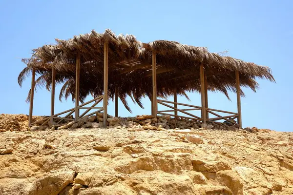 Ziyaretçiler, Kızıl Deniz 'in güzel bir noktası olan Hurghada' daki Cennet Adası 'nda bir plaj şemsiyesi tarafından sağlanan gölgenin keyfini çıkarıyorlar. Huzurlu atmosfer dinlenmeyi ve boş zamanı davet eder..