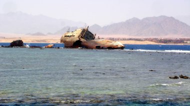 Bir gemi enkazının kalıntıları kısmen Kızıl Deniz 'de yatıyordu. Paslı metaller ve terk edilmiş yapılar Sina dağlarına karşı sergileniyordu. Bir zamanlar faaliyet gösteren bir geminin sonunu işaret ediyordu..