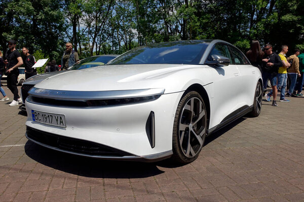 Lviv, Ukraine - June 1, 2023 A sleek white electric vehicle stands prominently in an outdoor venue, attracting curious onlookers who admire its modern design and innovative features during