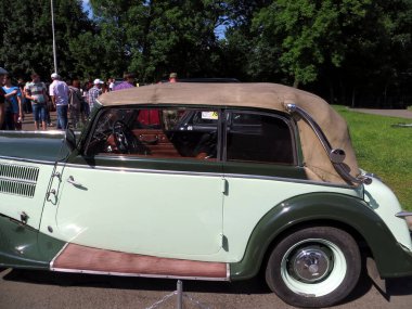 Lviv, Ukraine - June 5, 2016 A classic convertible car AUDI Front 225 1936 with a soft top is displayed at an outdoor gathering, drawing attention from onlookers clipart