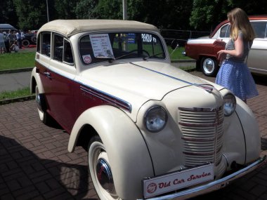 Lviv, Ukrayna - 5 Haziran 2016 ZMA Moskvitch 400-420 model, krema ve kestane rengi şeması içeren klasik bir araba, açık hava otomobil fuarında, genç bir kızla birlikte sergileniyor.