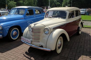 Lviv, Ukrayna - 5 Haziran 2016 Klasik otomobil ZMA Moskvitch 400-420 sergisi, mavi bir aracın yanına park edilmiş krema ve şarap rengi bir araba. Katılımcılar güneşli havanın tadını çıkarıyorlar