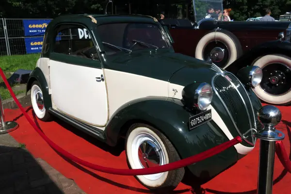 Lviv, Ukrayna - 5 Haziran 2016 Klasik bir otomobil sergisinde yeşil ve beyaz boyalı etkileyici bir klasik araba FIAT Topolino sergileniyor. Araç güneş ışığı altında kırmızı bir halıya park edilmiş.