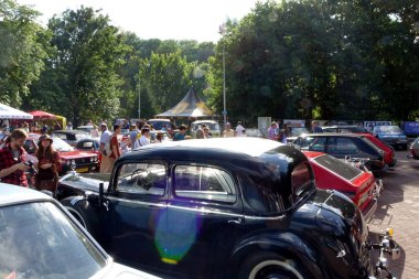 Lviv, Ukraine - June 6, 2017 A lively outdoor gathering features classic cars Mercedes-Benz 230 W143 1938 and numerous visitors enjoying the sunny weather clipart