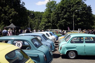 Lviv, Ukrayna - 1 Haziran 2023 ZAZ-965 Zaporozhets adlı canlı klasik bir otomobil, çeşitli renklerde klasik araçların yer aldığı bir parkta toplanır. Katılımcılar arabalara hayran.