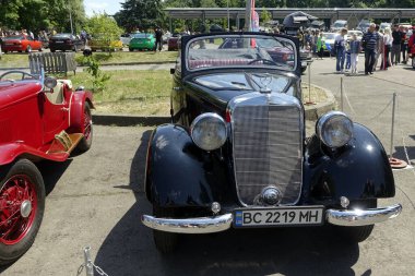 Lviv, Ukrayna - 1 Haziran 2023 Mercedes-Benz 170v parlak siyah üstü açık araba, ilgili izleyiciler tarafından çevrelenmiş klasik bir araba fuarında sergilenmektedir.