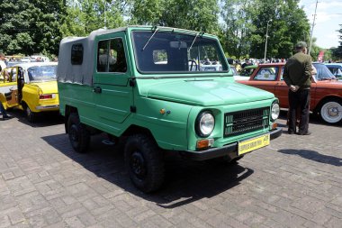 Lviv, Ukraine - June 1, 2023 A vintage green compact vehicle LUAZ 969M Volynyanka stands prominently among classic cars at an auto show, while enthusiasts admire the unique design and engage clipart