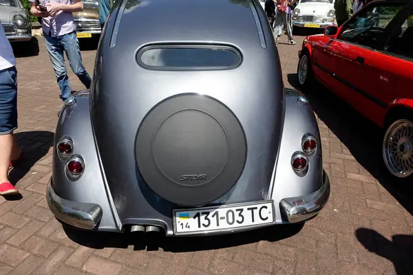 Lviv, Ukrayna - 1 Haziran 2023 Steyr 55 klasik araba meraklıları güneşli bir günde açık hava otomobil fuarı sırasında klasik bir aracın etrafında toplanarak benzersiz özelliklerini ve tarihini tartıştılar..