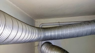 Yeni bir akaryakıt borusu, bir gaz kazanına bağlanıyor. Kurulumda duvar boyunca esnek borular sergilenerek verimli gaz akışı sağlanıyor.