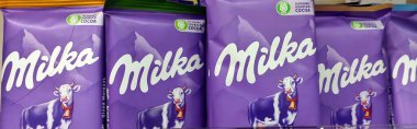 Lviv, Ukrayna - 16 Mayıs 2025 Milka çikolata paketleri düzgünce bir süpermarket rafına dizilmiştir. Ürünler parlak mor ambalajlar içeriyor, müşteriler için cazip bir görüntü oluşturuyor.