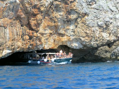 Herceg Novi Montenegro - 20 Temmuz 2014 Turistleri, Karadağ 'ın nefes kesici Blue Grotto' sunu keşfetmek için tekne gezisine çıktılar. Dalgalı mavi sular, açık bir gökyüzü altında çarpışan kaya oluşumlarını yansıtıyor..