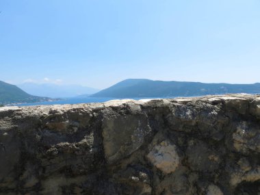 Ziyaretçiler, Herceg Novi 'ye bakan önemli bir tarihi yer olan Kanli Kula Kalesi' nden Boka Kotorska 'nın panoramik manzarasının keyfini çıkarıyorlar. Çarpıcı manzara herkesi cezbediyor..