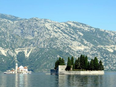Kotor Körfezi, güneşli bir günde heybetli dağlar ve sakin sularla çevrili Aziz George ve Kayalıklar Leydisi 'nin sakin adalarını sergiliyor..