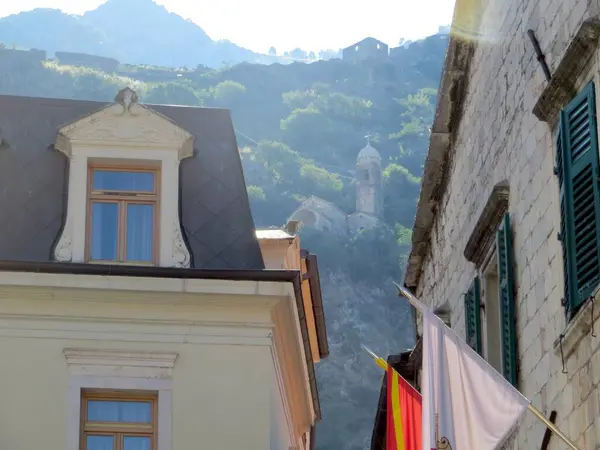 Büyüleyici binalar Kotors 'un eski kasabasının zengin tarihini yansıtırken uzak bir kilise yukarıdaki dağda huzur içinde oturup bu sahil taşının özünü yakalıyor..