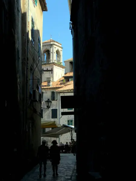 Ziyaretçiler, bu kıyı kasabasının eşsiz mimarisi ve hareketli atmosferine hayranlıkla bakarak, açık mavi gökyüzünün altındaki antik Kotor sokaklarında geziniyorlar..