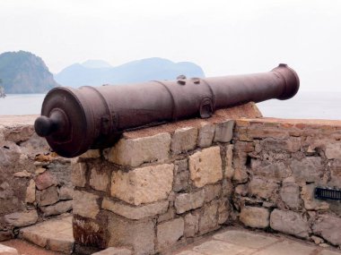 Karadağ 'ın Petrovac kentindeki taş duvarlarda duran eski bir top, sakin körfez ve uzak tepeleri görerek, tarih ve sükuneti anımsatıyor..