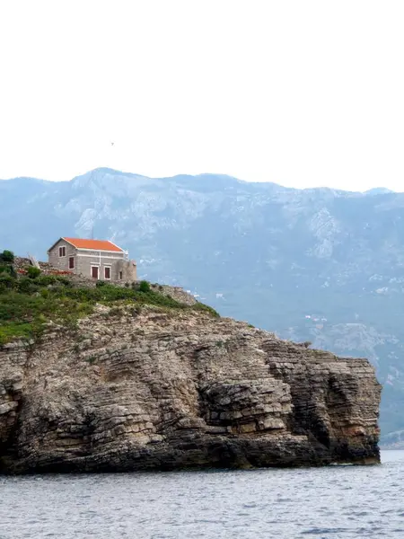 Sveti Nikola Adası 'ndaki küçük deniz feneri, Karadağ' ın engin Adriyatik Denizi ve çarpıcı dağ manzaralarıyla çevrili kayalık bir uçurumun üzerinde gururla duruyor..
