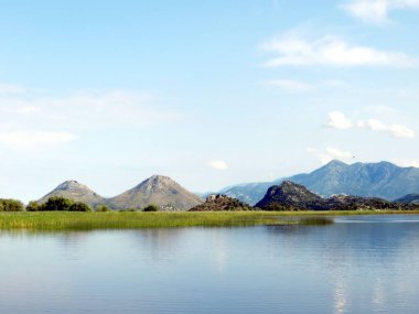 Skadar Gölü 'nün nefes kesici manzarası sakin suları, yemyeşil suları ve berrak bir gökyüzünün altındaki büyüleyici dağları gözler önüne seriyor. Doğa cenneti, keşif ve yansımayı davet eder..