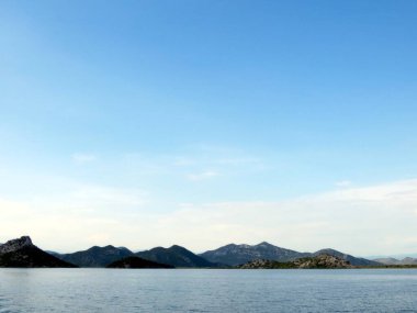 Parlak sular ve yemyeşil ve engebeli dağlarla çevrili Skadar Gölü 'nde berrak bir gökyüzü, Karadağ' da gezginler için nefes kesici bir zemin oluşturuyor.