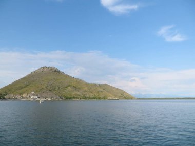 Bereketli yeşil tepeler Skadar Gölü 'nün dingin sularının yanında yükseliyor. Gezginleri doğanın tadını çıkarmaya davet ediyor..