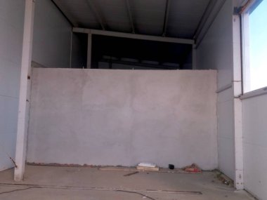 İşçiler ticari bir alana yeni bir duvar örüyor. Bölge yenileniyor ve çıplak yüzey ve inşaat malzemelerini gösteriyor.