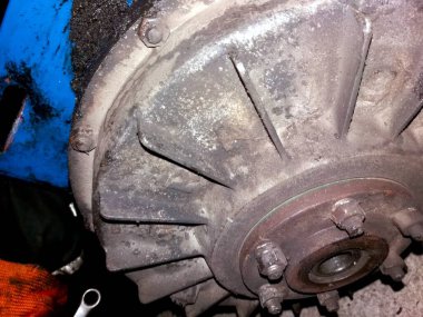 Onarım ve bakımların devam ettiği bir atölye ortamında, yıpranma ve kirlilik içeren bir hidrolik sürücü debriyajı gösteriliyor. Araçlar ve parçalar görünür.