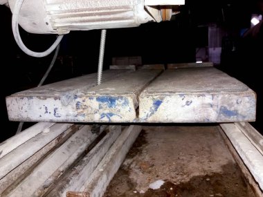 Bir atölyede, çeşitli inşaat ve sanat projeleri için büyük taş levhaları ustalıkla şekillendirilmiş bir taş kesme makinesi aktif olarak çalıştırılıyor..