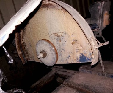 Bir taş kesme makinesi, toz ve molozlarla çevrili bir inşaat atölyesine yerleştiriliyor. Bu da yakın zamanda çeşitli projeler için taş malzemelerinin kesiminde kullanıldığını gösteriyor..