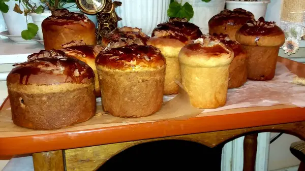 Ukrayna 'daki Paskalya pastaları ahşap bir masaya oturup altın kabuklarını ve tatlı malzemelerini sergiliyorlar. Etrafları yeşilliklerle çevrili, şenlikli toplantıları ve neşeli anları bekliyorlar..